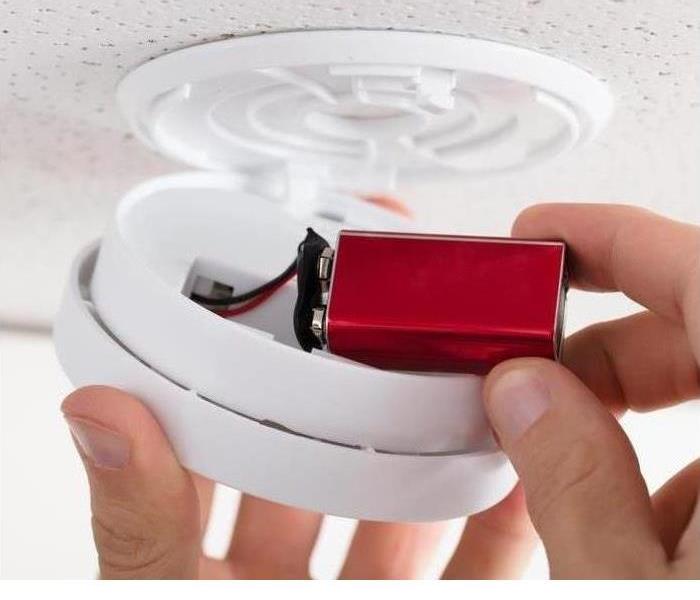 A battery is shown being put into a smoke alarm
