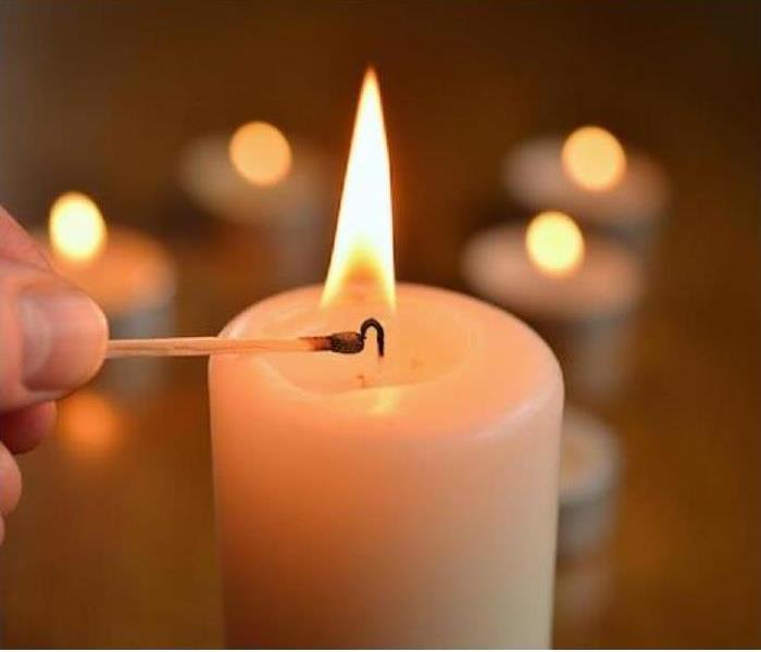 A candle is shown being lit with other candles in background
